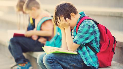 Boy sitting on steps with head in his hands