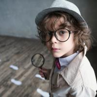 A child dressed as a detective with a magnifying glass
