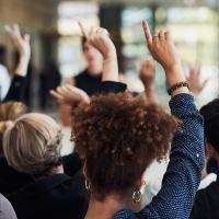 Crowd of people raising their hands for questions