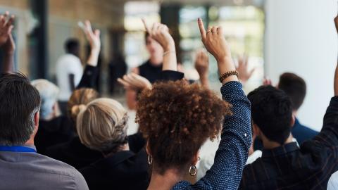 Crowd of people raising their hands for questions
