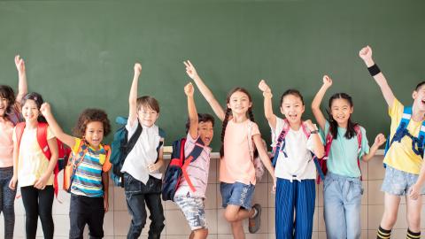 Diverse young students cheering at blackboard