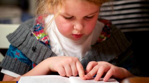 Girl reading book while moving her finger