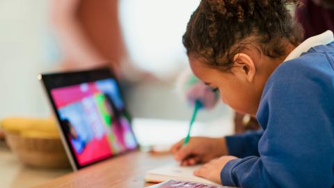 Young girl writing with iPad in front of her