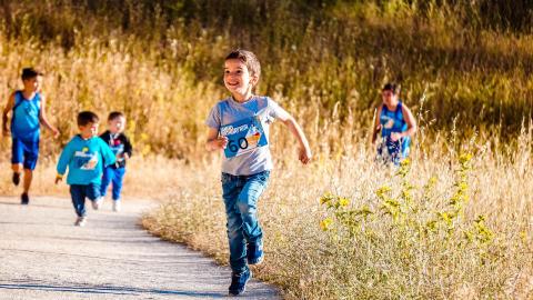 Young boys running down path through a field with racing numbers pinned to shirts