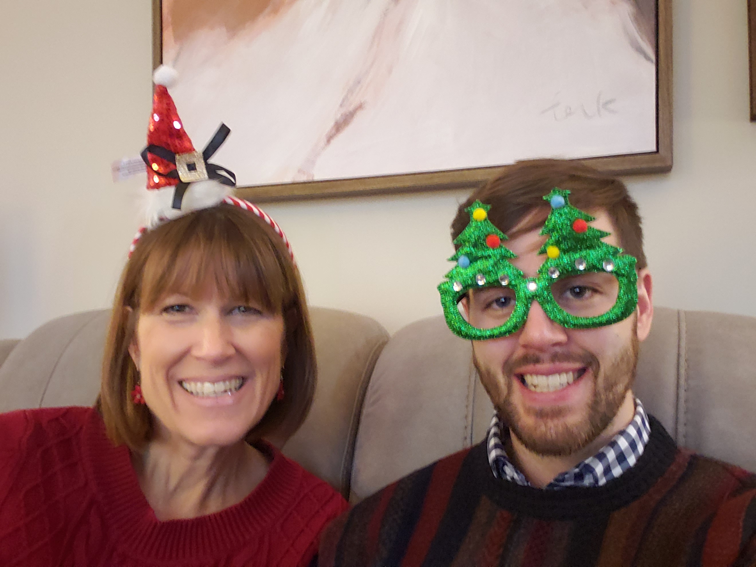 Susan and an adult Justin wearing holiday hats and glasses.