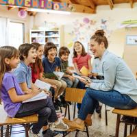 Teacher laughing with kids who are holding notebooks