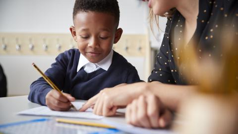Teacher helping boy with his writing
