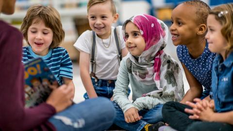 Teacher reading to kids on the floor