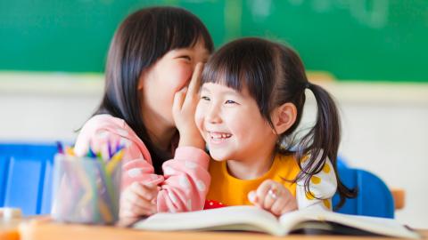 Two girls whispering and smiling