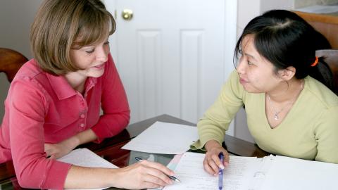 woman working with girl on homework