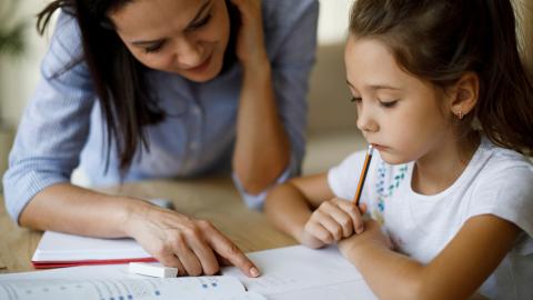 Woman working with girl on schoolwork