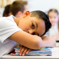 A young student with his head down on his desk.