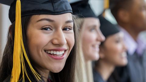Smiling young woman in a cap and gown